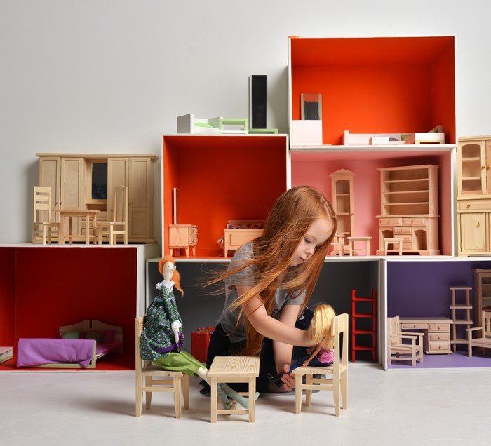 Girl playing with dolls in a dollhouse