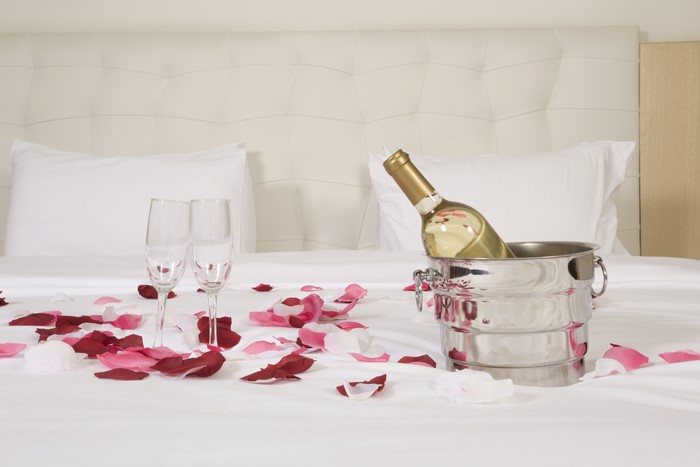 Wine bottle and glasses on a bed with petals
