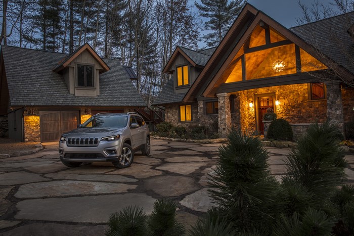 2019 Jeep Cherokee Limited parked in front of a stone mansion at dusk