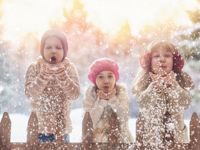 Three little girls blowing snow in winter