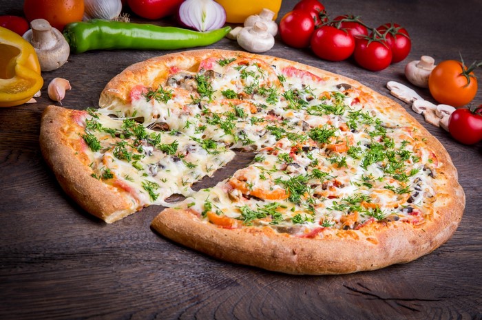 Pizza with cheese and herbs on a wooden table