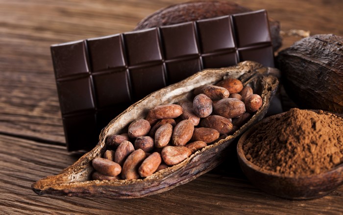 Chocolate bar, cocoa beans, and cocoa powder on wood