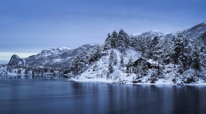 Snowy mountains and lake with a house in Norway