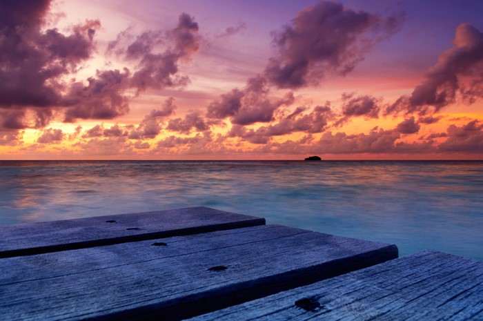 Wooden pier at sunset over the ocean in the Maldives