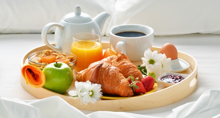 Breakfast tray with croissants, fruit, coffee, and juice