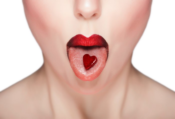 Red lips with heart on tongue on white background