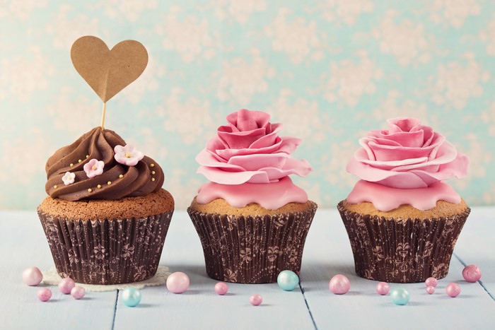 Three cupcakes with chocolate and pink frosting, heart topper
