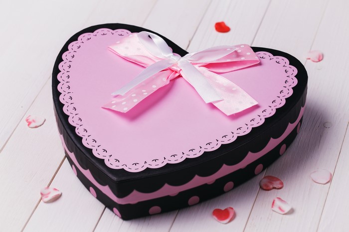 Heart-shaped gift box with bow on wood planks