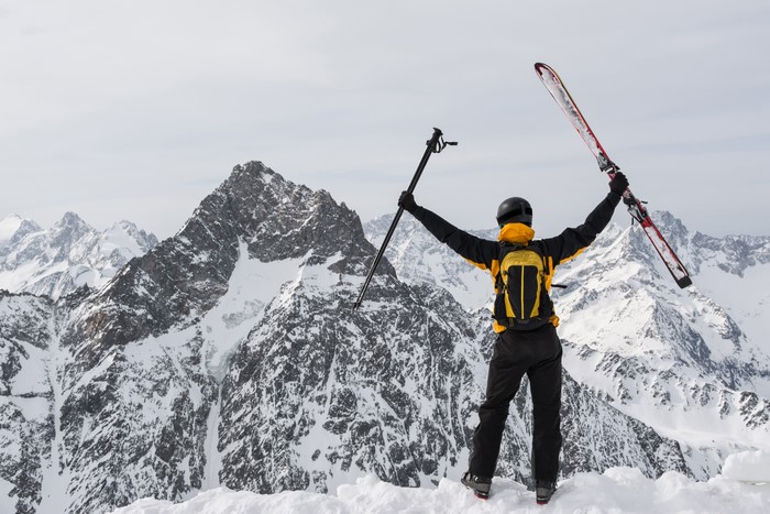 Skier with skis and poles on snowy mountain peak
