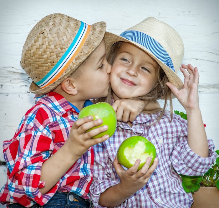 Boy kissing girl holding apples