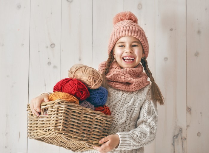 Girl in Winter Hat Holding Wicker Basket of Yarn