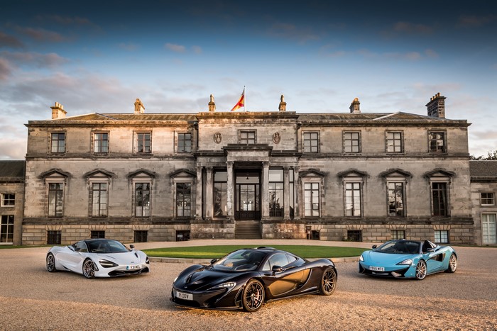 Three McLaren cars in front of a mansion