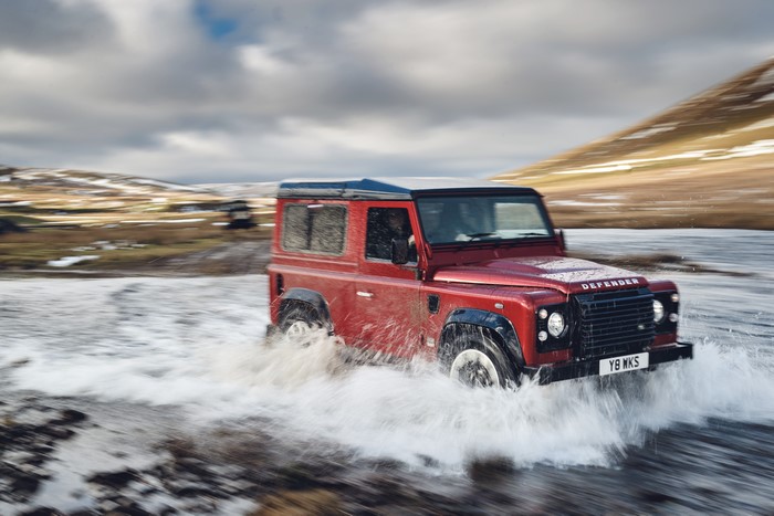 Red Land Rover Defender Works V8 driving through water