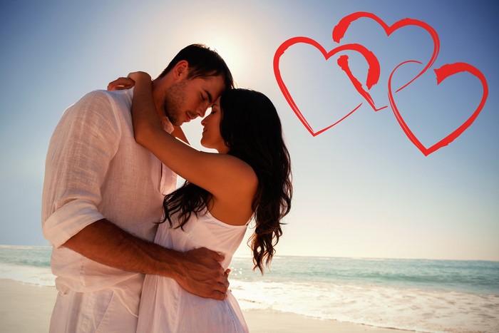 Couple hugging on beach with hearts