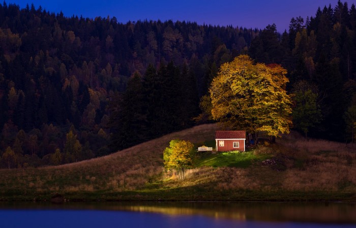Red house on a hill in Norway during autumn evening
