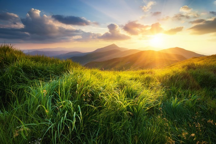 Sunrise over grassy hills with clouds