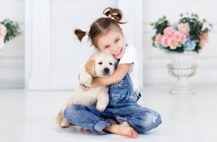 Girl Hugging Golden Retriever Puppy