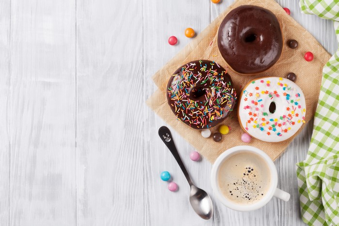 Three donuts with coffee and candy on wood planks