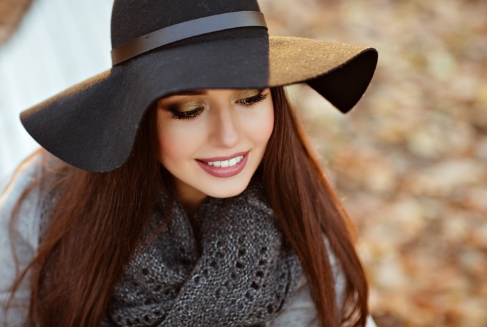Woman with brown hair wearing a black hat and scarf