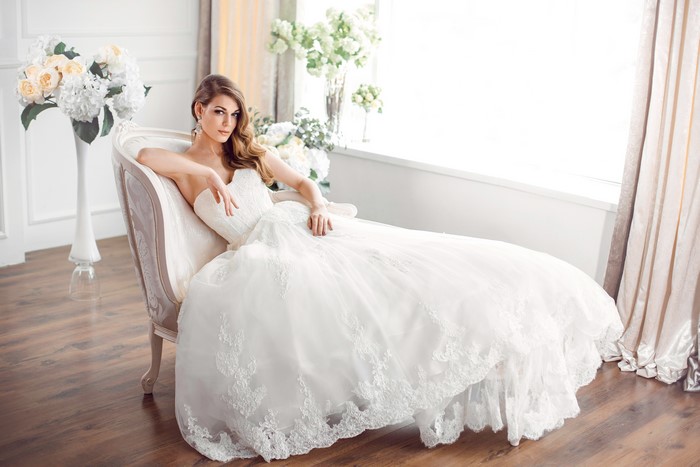 Bride in a white dress sitting on a chaise lounge