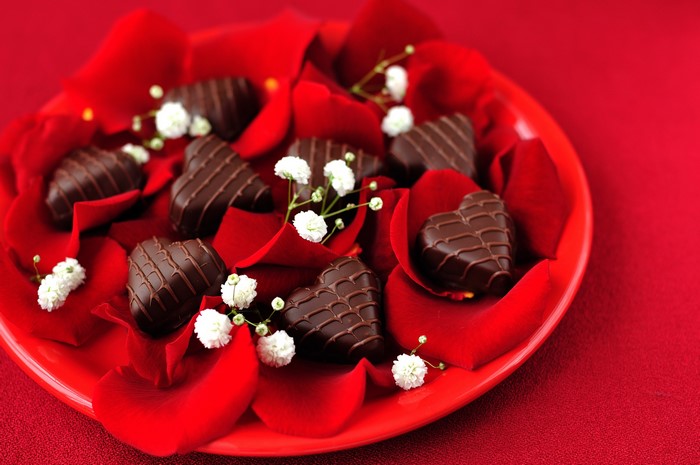 Heart-shaped chocolates on red rose petals