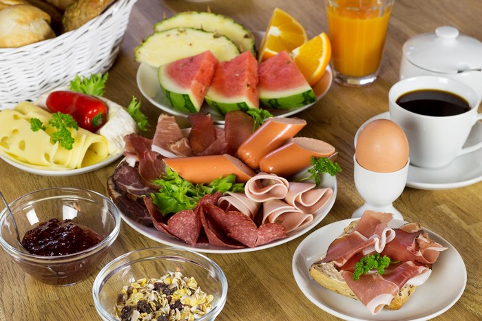 Breakfast spread with sausages, cheese, fruit, and coffee