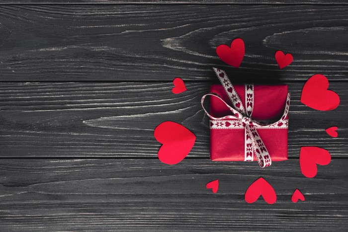 Red gift box with hearts on dark wood