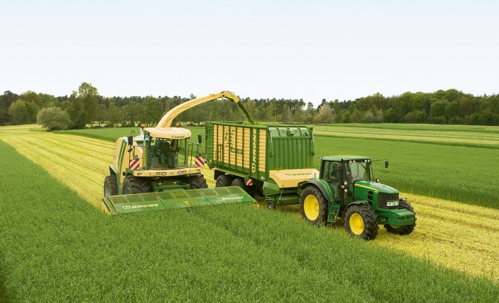Krone BiG M and John Deere tractor harvesting a field