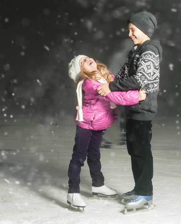 Two children ice skating in the snow