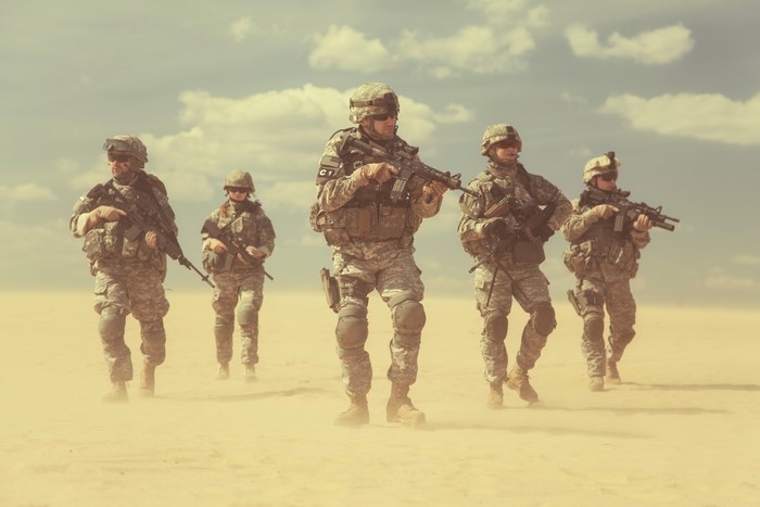 Soldiers in uniform with assault rifles in desert