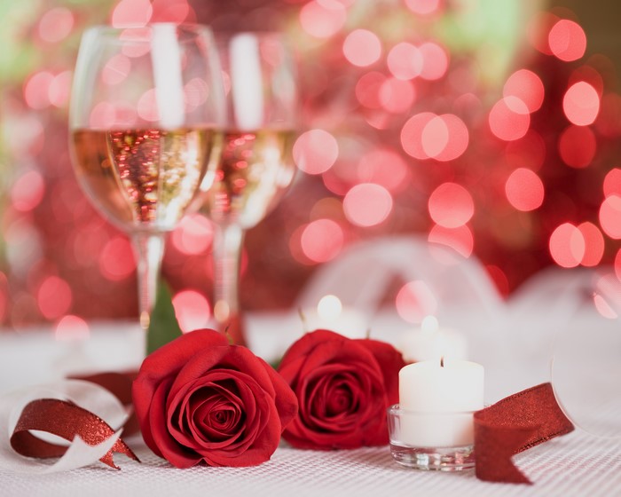 Two glasses of champagne with red roses and candles