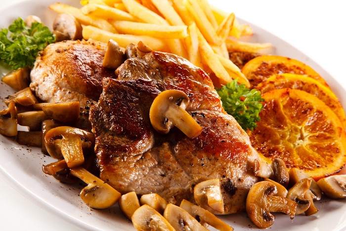 Meat with mushrooms, french fries, and orange slices