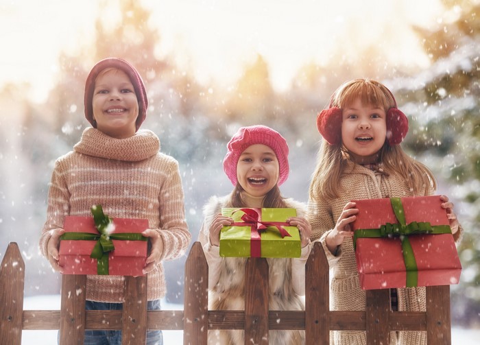 Three Children Holding Christmas Gifts in Snow
