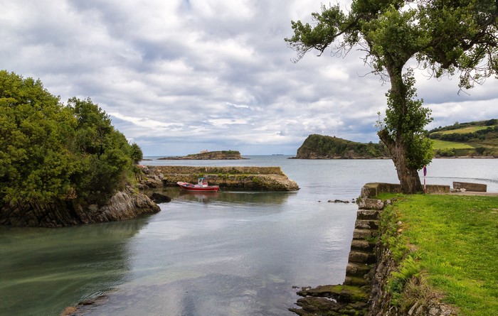 Small red boat in a bay with islands and trees
