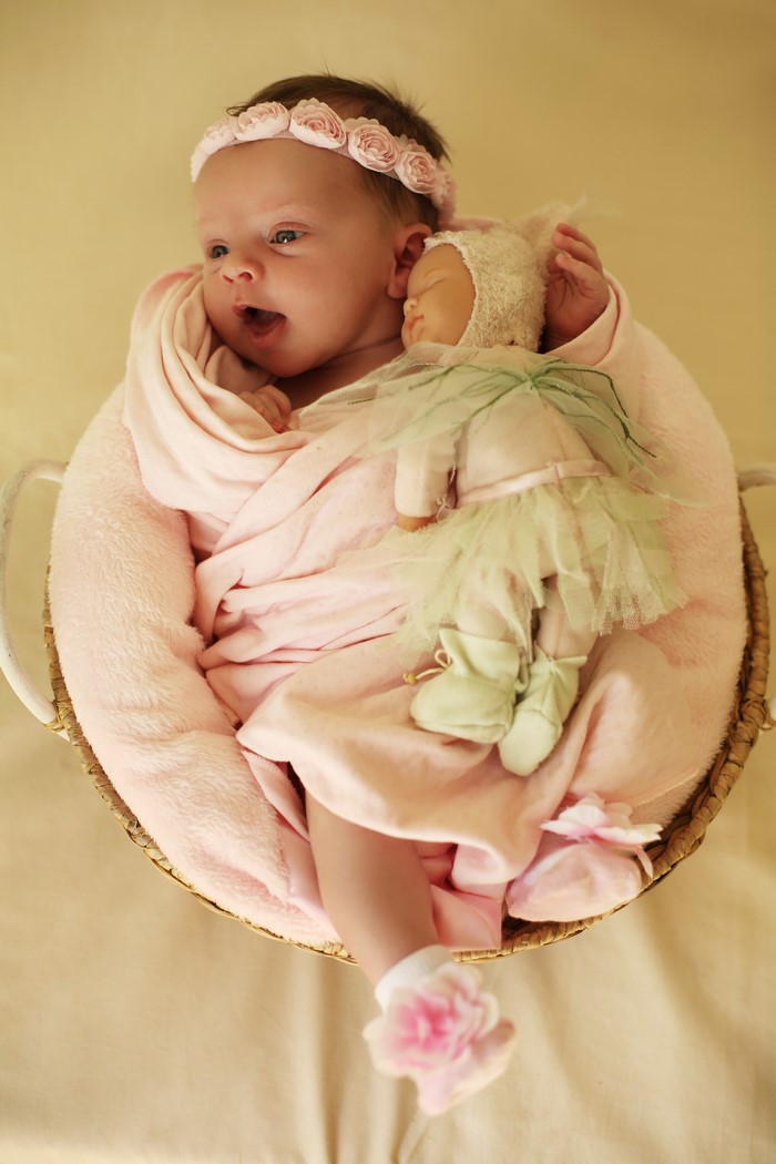 Baby girl with doll in a basket
