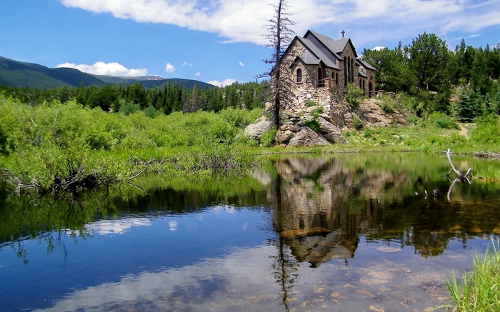 Chapel on a rocky outcrop reflected in a pond