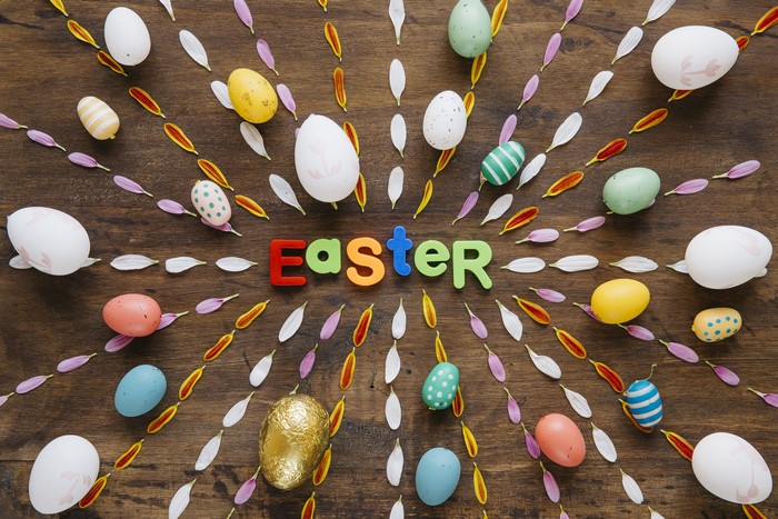 Easter word with eggs and petals on wooden background