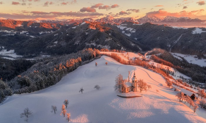 Church in snowy mountains at sunset, Slovenia