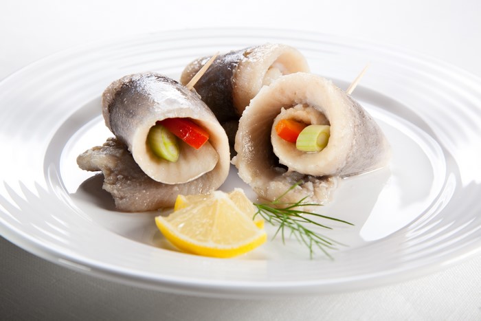 Rollmops with vegetables and lemon on a plate