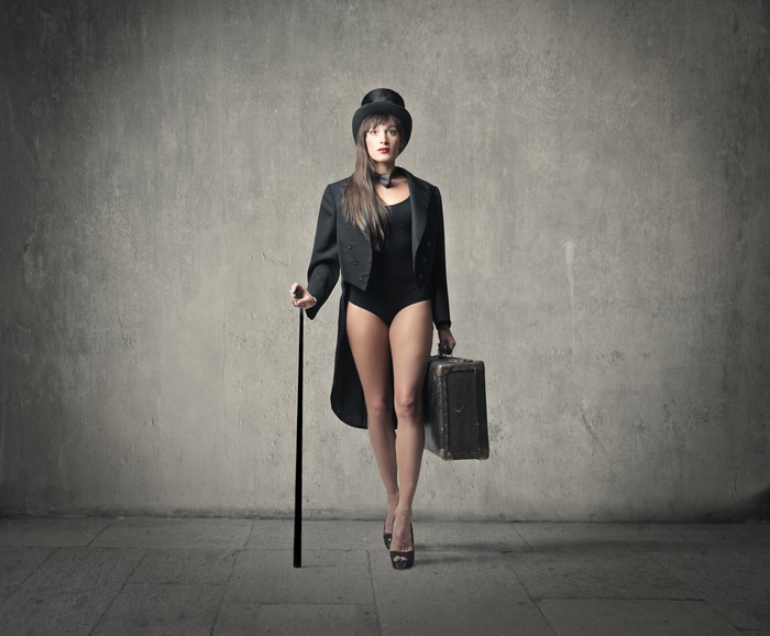 Woman in Top Hat and Suit Holding Cane and Suitcase