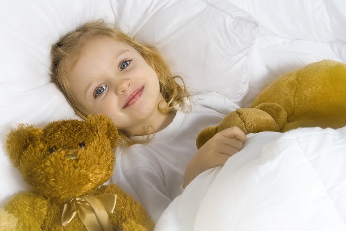 Little girl with teddy bears in bed