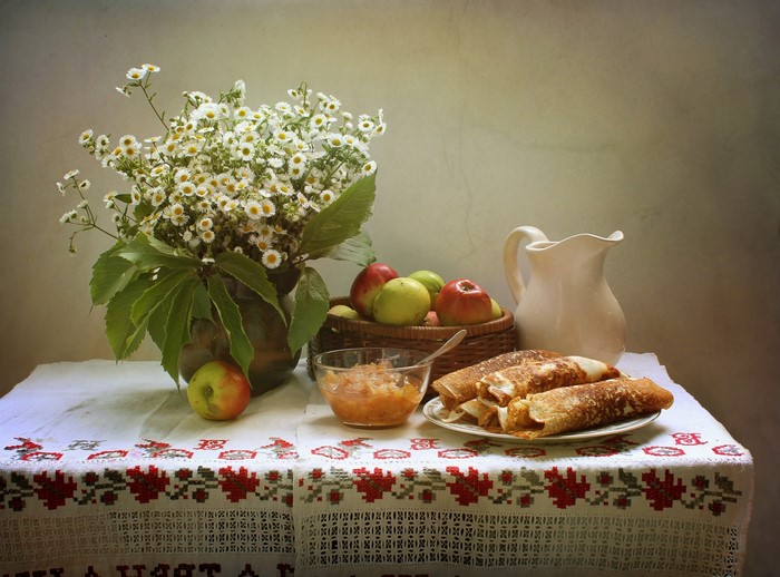 Still life with camomiles, apples, pancakes, and a jug