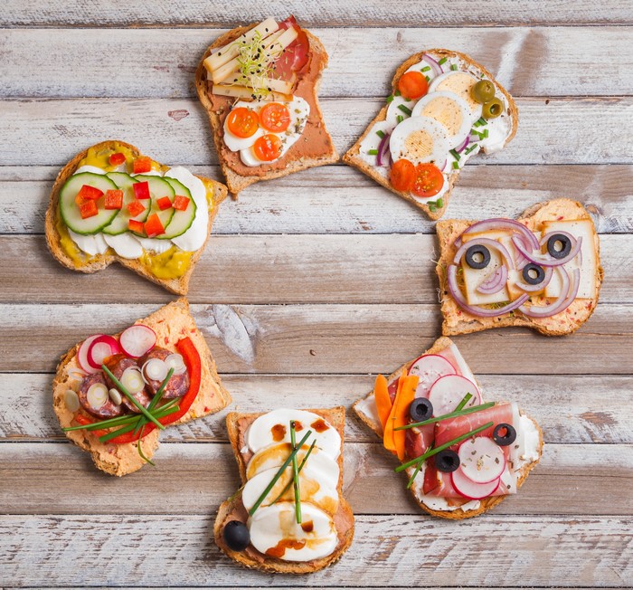 Assortment of open-faced sandwiches with various toppings on wooden table