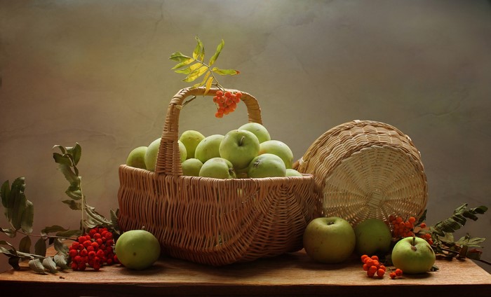 Still-life with apples and rowan berries in a wicker basket
