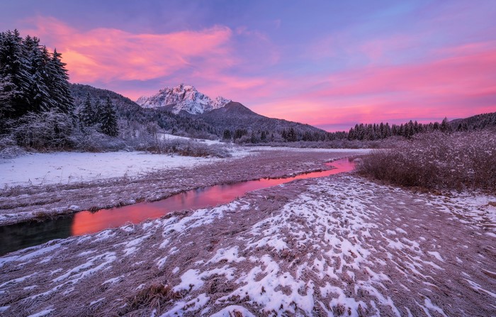 Winter sunrise over mountains and stream in Slovenia