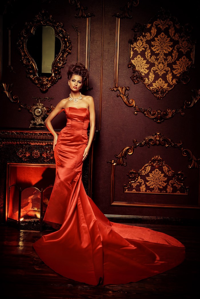 Woman in a red dress standing by a fireplace