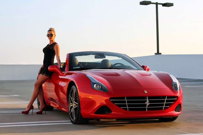 Woman in black dress with red Ferrari California