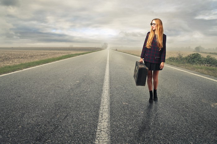 Redhead girl with suitcase on a road