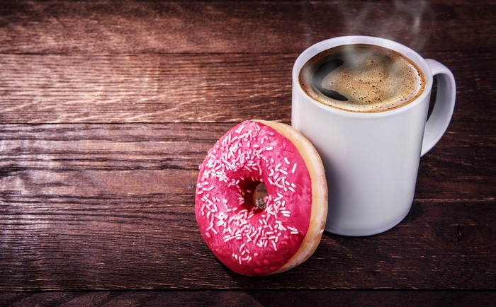 Coffee and a pink donut on wood planks