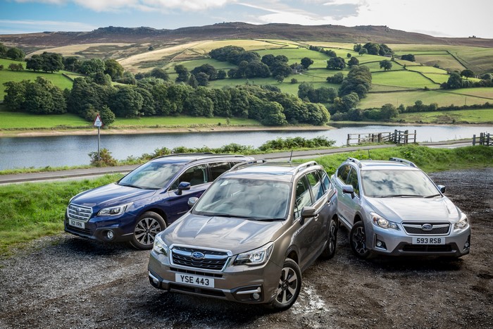 Three Subaru SUVs parked by a reservoir